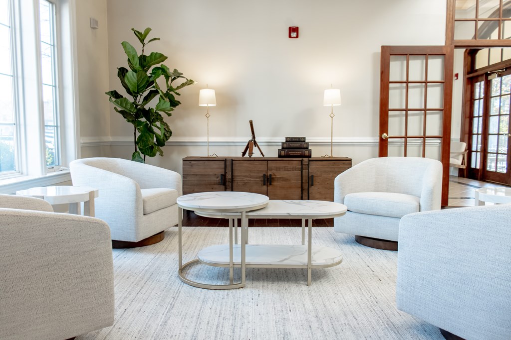 a living room with white chairs and a coffee table at Broadlands Apartments in Ashburn